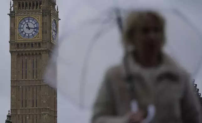 A woman holds an umbrella as she walks on Westminster Bridge over the River Thames with the clock face of Queen Elizabeth Tower in the background in London, Friday, May 3, 2024. Britain's governing Conservative Party is suffering heavy losses as local election results pour in Friday, piling pressure on Prime Minister Rishi Sunak ahead of a U.K. general election in which the main opposition Labour Party appears increasingly likely to return to power after 14 years. The Queen Elizabeth Tower holds the bell known as Big Ben. (AP Photo/Kin Cheung)