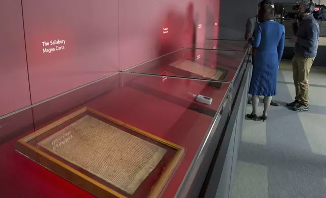 FILE - members of the media film four of the original surviving Magna Carta manuscripts that have been brought together by the British Library for the first time, during a media preview in London, Monday, Feb. 2, 2015. Two environmental activists have attacked a glass case containing an original copy of the Magna Carta at the British Library, causing minor damage to the re-enforced box but leaving the historic document unscathed on Friday, May 10, 2024. (AP Photo/Alastair Grant, File)