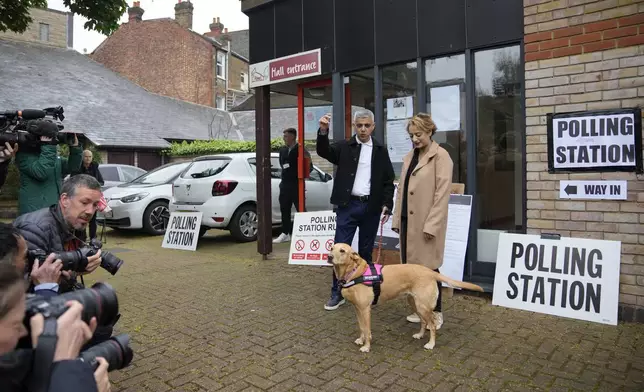 London Mayoral Labour Party candidate Sadiq Khan and his wife Saadiya Ahmed with their dog Luna pose for the media as they arrive to vote in London, Thursday, May 2, 2024. Khan, is seeking re-election, and standing against 12 other candidates for the post of Mayor of London. There are other Mayoral elections in English cities and as well as local council elections. (AP Photo/Kin Cheung)
