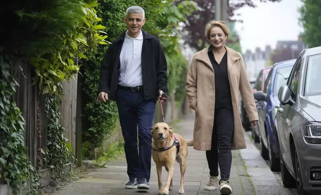 London Mayoral Labour Party candidate Sadiq Khan and his wife Saadiya Ahmed with their dog Luna, pose for the media as they arrive to vote in London, Thursday, May 2, 2024. Khan, is seeking re-election, and standing against 12 other candidates for the post of Mayor of London. There are other Mayoral elections in English cities and as well as local council elections. (AP Photo/Kin Cheung)