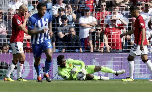 Manchester United goalkeeper Andre Onana, centre, makes a save, during the English Premier League soccer match between Brighton &amp; Hove Albion and Manchester United, at the Amex Stadium, in Brighton and Hove, England, Sunday, May 19, 2024. (Steven Paston/PA via AP)