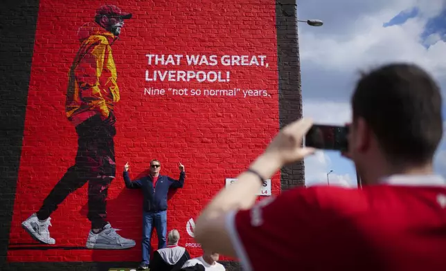 A fan poses for photos next to a mural with the image of Liverpool’s manager Jurgen Klopp prior to the English Premier League soccer match between Liverpool and Tottenham Hotspur at Anfield Stadium in Liverpool, England, Sunday, May 5, 2024. (AP Photo/Jon Super)