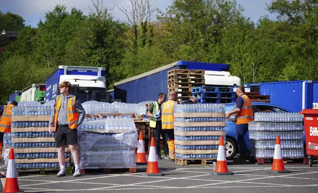 People collect bottled water at Broadsands Car Park in Paignton, England, Friday May 17, 2024. Around 16,000 households and businesses in the Brixham area of Devon have been told not to use their tap water for drinking without boiling and cooling it first, following the discovery of small traces of a parasite in the local water network. (Ben Birchall/PA via AP)