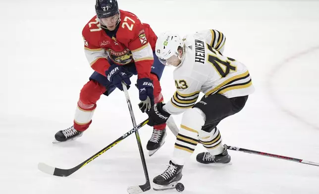 Boston Bruins center Danton Heinen (43) and Florida Panthers center Eetu Luostarinen (27) battle for the puck during the second period of Game 5 of the second-round series of the Stanley Cup Playoffs, Tuesday, May 14, 2024, in Sunrise, Fla. (AP Photo/Wilfredo Lee)