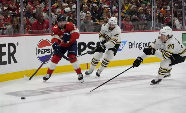 Florida Panthers center Evan Rodrigues (17), Boston Bruins defenseman Derek Forbort, center, and center Jesper Boqvist (70) go for the puck during the second period of Game 2 of a second-round series of the NHL hockey Stanley Cup playoffs Wednesday, May 8, 2024, in Sunrise, Fla. (AP Photo/Lynne Sladky)
