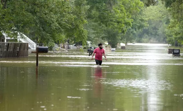 CORRECTS CITY TO WOODLOCH NOT WOODLOCK - A man walks through floodwaters on River Oaks Drive, Saturday, May 4, 2024, in Woodloch, Texas. (Karen Warren/Houston Chronicle via AP)