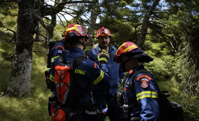 Fire Lt Col Ioannis Kolovos, head of the 1st Wildfire Special Operation Unit, center, speaks with the members of his team during a drill near Villia village some 60 kilometers (37 miles) northwest of Athens, Greece, Friday, April 19, 2024. Greece's fire season officially starts on May 1 but dozens of fires have already been put out over the past month after temperatures began hitting 30 degrees Celsius (86 degrees Fahrenheit) in late March. This year, Greece is doubling the number of firefighters in specialized units to some 1,300, adopting tactics from the United States to try and outflank fires with airborne units scrambled to build breaks in the predicted path of the flames. (AP Photo/Thanassis Stavrakis)