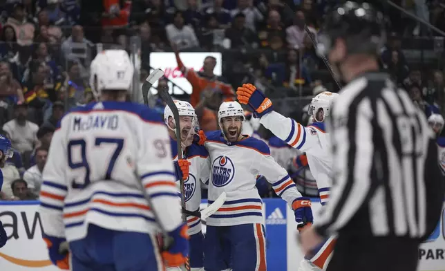 CORRECTS GOAL SCORER TO ZACH HYMAN NOT EVAN BOUCHARD - Edmonton Oilers defenseman Evan Bouchard (2) celebrates with teammates Connor McDavid (97), Zach Hyman (18), Ryan Nugent-Hopkins, third from left, and Mattias Ekholm, fifth from right, after a goal by Hyman during the second period in Game 7 of an NHL hockey Stanley Cup second-round playoff series against the Vancouver Canucks in Vancouver, British Columbia, Monday, May 20, 2024. (Darryl Dyck/The Canadian Press via AP)