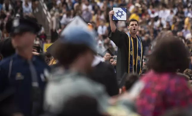 Graduates sporting Israeli flags and pins shout at Pro-Palestinian protesters as they demonstrate during the University of Michigan's Spring 2024 Commencement Ceremony at Michigan Stadium in Ann Arbor, Mich., on Saturday, May 4, 2024. (Katy Kildee/Detroit News via AP)