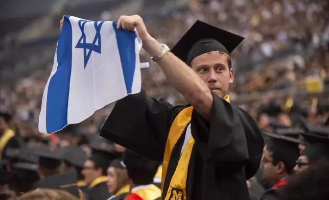 Graduates sporting Israeli flags and pins shout at Pro-Palestinian protesters as they demonstrate during the University of Michigan's Spring 2024 Commencement Ceremony at Michigan Stadium in Ann Arbor, Mich., on Saturday, May 4, 2024. (Katy Kildee/Detroit News via AP)