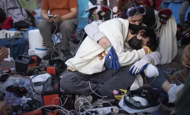 FILE - Pro-Palestinian demonstrators embrace while charging devices at an encampment on the UCLA campus Wednesday, May 1, 2024, in Los Angeles. (AP Photo/Ethan Swope, File)