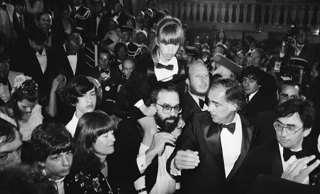 FILE - American director Francis Ford Coppola, center, carries his daughter Sofia, 8, through the crowd after the formal presentation of the U.S. film "Apolalypse Now", at the Cannes International Film Festival in France on May 19, 1979. His son Gian Carlo, 15, and his wife Ellie are left. Coppola is back at Cannes with his latest film "Megalopolis." (AP Photo/Jean-Jacques Levy, File)