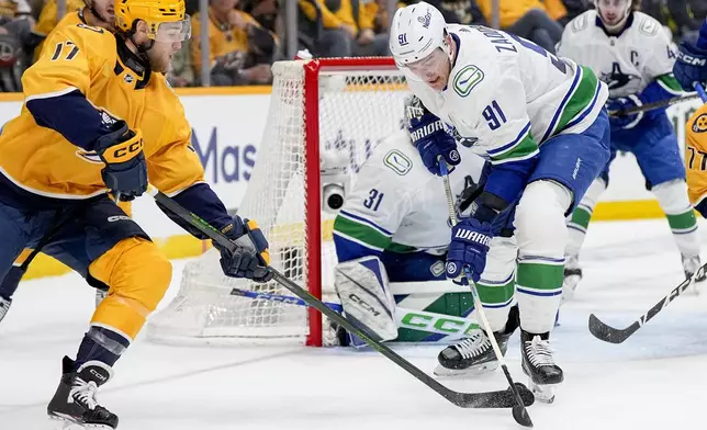 Nashville Predators center Mark Jankowski (17) tries to get the puck past Vancouver Canucks defenseman Nikita Zadorov (91) during the second period in Game 6 of an NHL hockey Stanley Cup first-round playoff series Friday, May 3, 2024, in Nashville, Tenn. (AP Photo/George Walker IV)