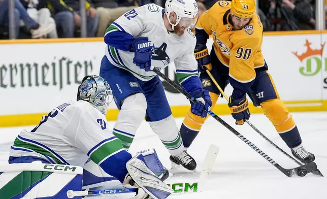 Vancouver Canucks defenseman Ian Cole (82) passes the puck away from Nashville Predators center Ryan O'Reilly (90) during the second period in Game 6 of an NHL hockey Stanley Cup first-round playoff series Friday, May 3, 2024, in Nashville, Tenn. (AP Photo/George Walker IV)