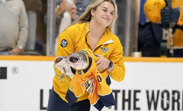 An ice worker skates off the ice with a pair of catfish before the start of Game 6 of an NHL hockey Stanley Cup first-round playoff series between the Nashville Predators and the Vancouver Canucks, Friday, May 3, 2024, in Nashville, Tenn. (AP Photo/George Walker IV)