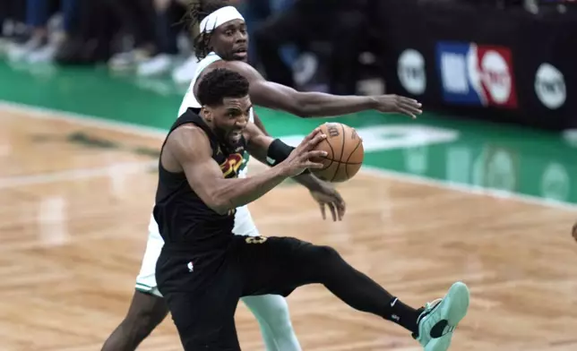 Cleveland Cavaliers guard Donovan Mitchell, front, grabs a rebound next to Boston Celtics guard Jrue Holiday during the first half of Game 1 of an NBA basketball second-round playoff series Tuesday, May 7, 2024, in Boston. (AP Photo/Charles Krupa)