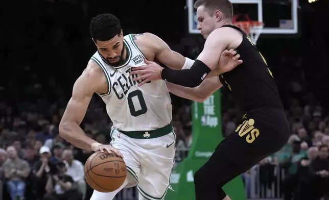 Boston Celtics forward Jayson Tatum (0) tries to break free from Cleveland Cavaliers guard Sam Merrill on a drive to the basket during the first half of Game 1 of an NBA basketball second-round playoff series Tuesday, May 7, 2024, in Boston. (AP Photo/Charles Krupa)