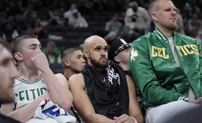 Boston Celtics guard Payton Pritchard, left, guard Derrick White, center, and center Kristaps Porzingis, right, watch from the bench as the Cleveland Cavaliers lead the Celtics during the second half of Game 2 of an NBA basketball second-round playoff series, Thursday, May 9, 2024, in Boston. (AP Photo/Steven Senne)