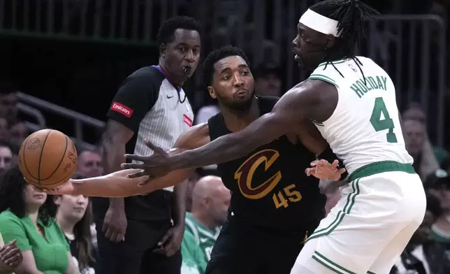 Cleveland Cavaliers guard Donovan Mitchell (45) looks to pass while pressured by Boston Celtics guard Jrue Holiday (4) during the second half of Game 1 of an NBA basketball second-round playoff series Tuesday, May 7, 2024, in Boston. (AP Photo/Charles Krupa)
