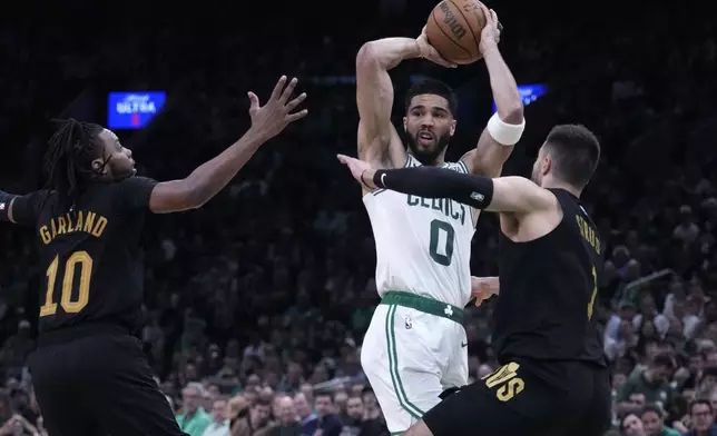 Boston Celtics forward Jayson Tatum (0) looks to pass while covered by Cleveland Cavaliers' Max Strus, right, and Darius Garland (10) during the first half of Game 1 of an NBA basketball second-round playoff series Tuesday, May 7, 2024, in Boston. (AP Photo/Charles Krupa)