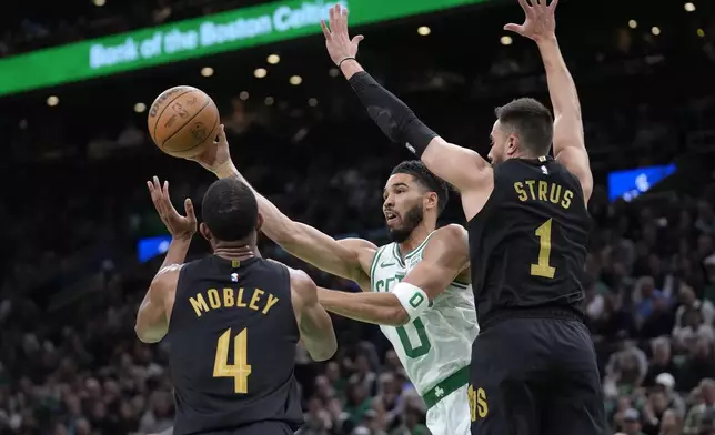 Boston Celtics forward Jayson Tatum (0) passes the ball as Cleveland Cavaliers forward Evan Mobley (4) and guard Max Strus (1) defend during the first half of Game 2 of an NBA basketball second-round playoff series Thursday, May 9, 2024, in Boston. (AP Photo/Steven Senne)
