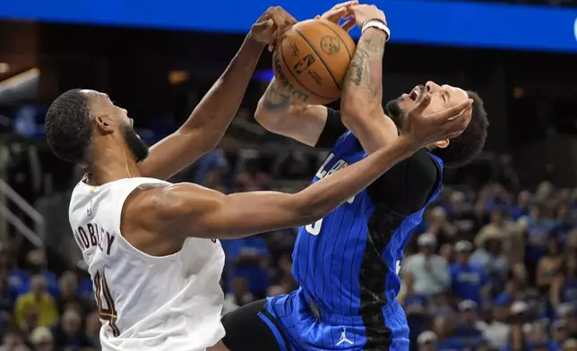 Cleveland Cavaliers forward Evan Mobley, left, fouls Orlando Magic guard Cole Anthony as he goes up for a shot during the second half of Game 6 of an NBA basketball first-round playoff series, Friday, May 3, 2024, in Orlando, Fla. (AP Photo/John Raoux)