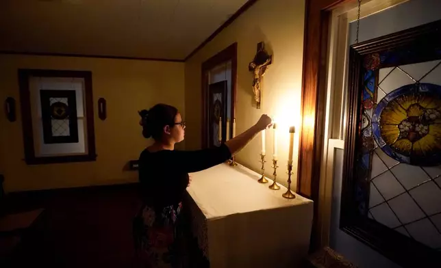 Benedictine College student Hannah Moore extinguishes candles after evening prayers with her roommates in a room which they converted to a chapel in the house they share Sunday, Dec. 3, 2023, in Atchison, Kan. (AP Photo/Charlie Riedel)