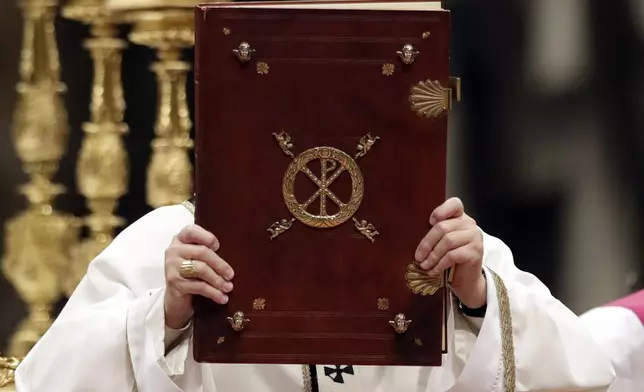 FILE - Pope Francis holds the book of the Gospels as he celebrates the Christmas Eve Mass in St. Peter's Basilica at the Vatican, Saturday, Dec. 24, 2016. (AP Photo/Alessandra Tarantino, File)