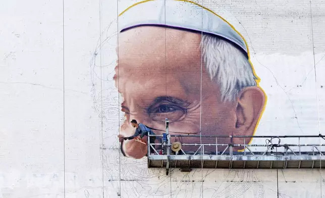 FILE - A painter outlines the Pope's nose on the side of a building in New York on Thursday, Aug. 27, 2015, a month before the visit of Pope Francis. (AP Photo/Mark Lennihan, File)