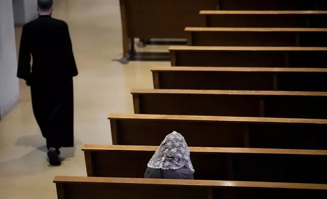 A woman sits alone before Catholic Mass at Benedictine College Sunday, Oct. 29, 2023, in Atchison, Kan. (AP Photo/Charlie Riedel)