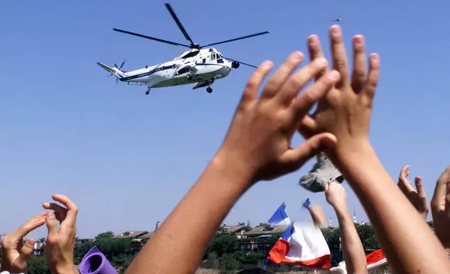 FILE - Youths wave goodbye to the helicopter carrying Pope John Paul II, as the Pontiff leaves the grounds of Tor Vergata after leading a Sunday Mass for some 2 million youths on Aug. 20, 2000. (AP Photo/Enric Marti, File)