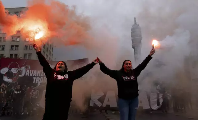 Protesters hold flares as they march on International Workers' Day in Santiago, Chile, Wednesday, May 1, 2024. (AP Photo/Matias Basualdo)