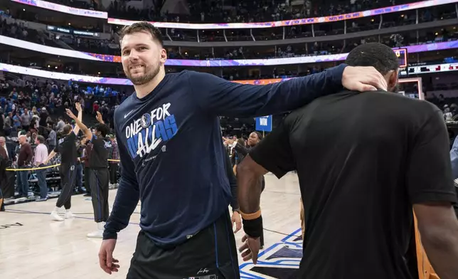 Dallas Mavericks' Luka Doncic, left, congratulates teammate Kyrie Irving as Irving speaks to the media after beating the Los Angeles Clippers 114-101 in Game 6 of an NBA basketball first-round playoff series Friday, May 3, 2024, in Dallas. (AP Photo/Jeffrey McWhorter)