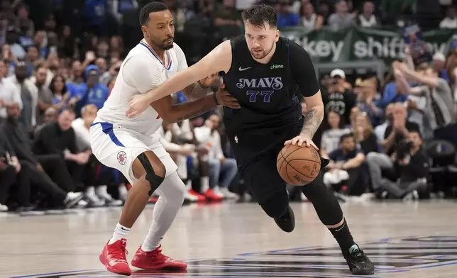 Dallas Mavericks guard Luka Doncic (77) drives past Los Angeles Clippers guard Norman Powell during the fourth quarter of an NBA basketball first-round playoff series Friday, May 3, 2024, in Dallas. (AP Photo/Jeffrey McWhorter)