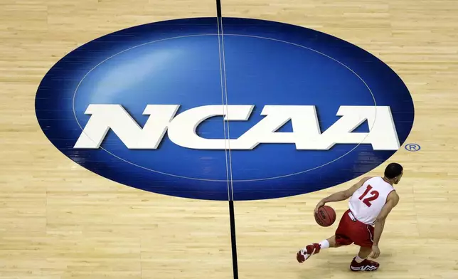 FILE - Wisconsin's Traevon Jackson dribbles past the NCAA logo during practice at the NCAA men's college basketball tournament March 26, 2014, in Anaheim, Calif. University presidents around the country are scheduled to meet this week in May 2024, to vote on whether to accept a proposed settlement of an antitrust lawsuit that would cost the NCAA nearly $3 billion in damages. (AP Photo/Jae C. Hong, File)