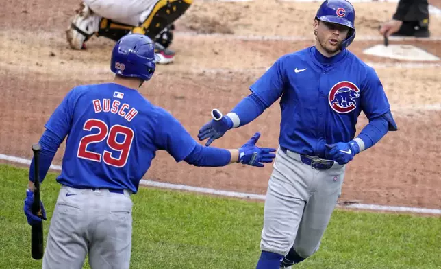 Chicago Cubs' Nico Hoerner, right, is greeted by Michael Busch (29) as he returns to the dugout after hitting a solo home run off Pittsburgh Pirates starting pitcher Paul Skenes during the fourth inning of a baseball game in Pittsburgh, Saturday, May 11, 2024. (AP Photo/Gene J. Puskar)