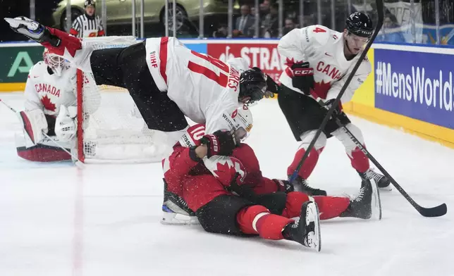 Canada's Bowen Byram, right, skates past as Canada's John Tavares, left, challenges Switzerland's Andres Ambuhl during the semifinal match between Canada and Switzerland at the Ice Hockey World Championships in Prague, Czech Republic, Saturday, May 25, 2024. (AP Photo/Petr David Josek)
