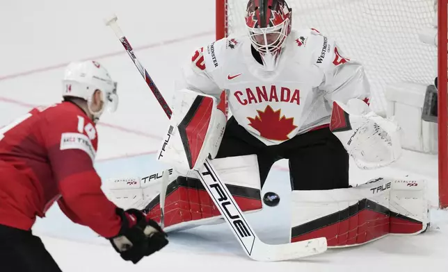 Canada's goldkeeper Jordan Binnington, right, makes a save in front of Switzerland's Dean Kukan during the semi final match between Canada and Switzerland at the Ice Hockey World Championships in Prague, Czech Republic, Saturday, May 25, 2024. (AP Photo/Darko Vojinovic)