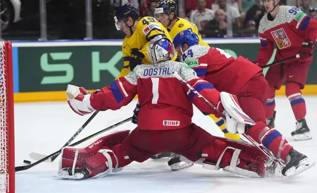 Czech Republic's goalkeeper Lukas Dostal, front, makes a save against Sweden's Fabian Zetterlund, back left, during the semifinal match between Czech Republic and Sweden at the Ice Hockey World Championships in Prague, Czech Republic, Saturday, May 25, 2024. (AP Photo/Petr David Josek)
