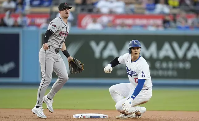 Arizona Diamondbacks shortstop Kevin Newman, left, throws over Los Angeles Dodgers' Shohei Ohtani, right, to compete a double play after a ground ball hit by Dodgers' Freddie Freeman during the first inning of a baseball game Monday, May 20, 2024, in Los Angeles. (AP Photo/Marcio Jose Sanchez)