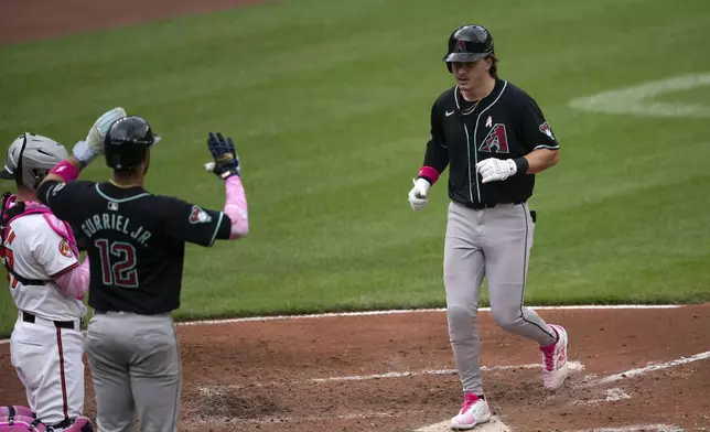 Arizona Diamondbacks' Jake McCarthy, right, scores during a baseball game against the Baltimore Orioles, Sunday, May 12, 2024, in Baltimore. (AP Photo/Jose Luis Magana)