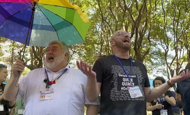 The Rev. David Meredith, left, and the Rev. Austin Adkinson sing during a gathering of those in the LGBTQ community and their allies outside the Charlotte Convention Center, in Charlotte, N.C., Thursday, May 2, 2024. They were celebrating after the General Conference of the United Methodist Church voted to remove the denomination's 52-year-old social teaching that deemed homosexuality "incompatible with Christian teaching." (AP Photo/Peter Smith)