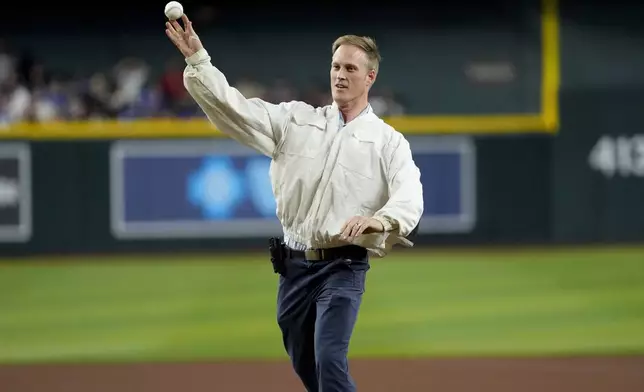 Bee keeper Matt Hilton throws out the ceremonial first pitch prior to a baseball game between the Los Angeles Dodgers and the Arizona Diamondbacks, Tuesday, April 30, 2024, in Phoenix. Hilton removed a swarm of bees on the net behind home plate that delayed the start of the game. (AP Photo/Matt York)
