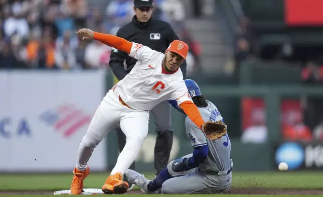 San Francisco Giants second baseman Thairo Estrada, left, is unable to reach the throw from catcher Blake Sabol as Los Angeles Dodgers' James Outman steals second during the third inning of a baseball game Tuesday, May 14, 2024, in San Francisco. Outman reached third on the throwing error by Sabol. (AP Photo/Godofredo A. Vásquez)
