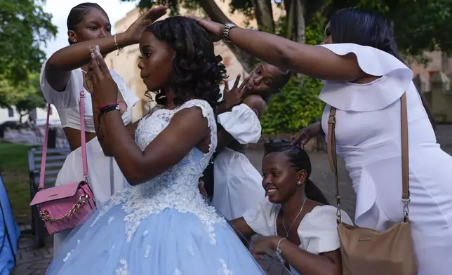 Friends and family fuss over a quinceañera in preparation for her photo session at Colon square in the Zona Colonial neighborhood of Santo Domingo, Dominican Republic, Wednesday, May 15, 2024. Dominicans head to the polls on Sunday, May 19th to elect a new president and members of their Congress. (AP Photo/Matias Delacroix)