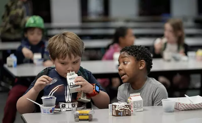 First graders Ripley Phillips, left, and Jabari Hall talk during breakfast at Williams Science and Arts Magnet school Friday, May 10, 2024, in Topeka, Kan. The school is just a block from the former Monroe school which was at the center of the Brown v. Board of Education Supreme Court ruling ending segregation in public schools 70 years ago. (AP Photo/Charlie Riedel)