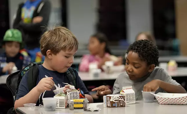 First graders Ripley Phillips, left, and Jabari Hall talk during breakfast at Williams Science and Arts Magnet school Friday, May 10, 2024, in Topeka, Kan. The school is just a block from the former Monroe school which was at the center of the Brown v. Board of Education Supreme Court ruling ending segregation in public schools 70 years ago. (AP Photo/Charlie Riedel)