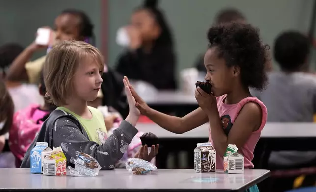 Third grader Katherine Nelson, left, and Shawn Kennedy, kindergarten, talk during breakfast at Williams Science and Arts Magnet school Friday, May 10, 2024, in Topeka, Kan. The school is just a block from the former Monroe school which was at the center of the Brown v. Board of Education Supreme Court ruling ending segregation in public schools 70 years ago. (AP Photo/Charlie Riedel)