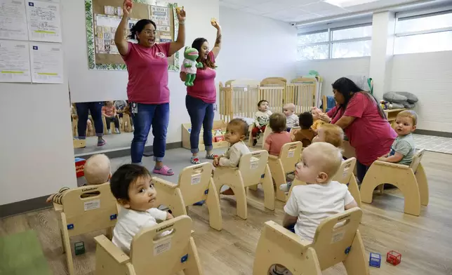 Caregivers Claudel Lepe, left, and Shyela Gonzaga, center, lead a song for a combined class of young infants and older infants at Little Mustangs Child Learning Academy, Wednesday, Feb. 21, 2024, in Richardson, Texas. (Elías Valverde II/The Dallas Morning News via AP)