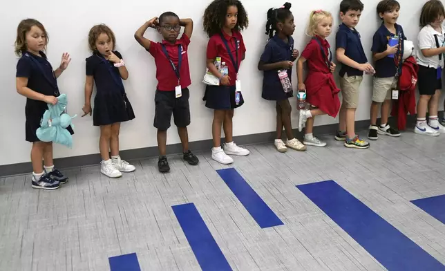 Elementary school students line up in a hall on their way to a class at A.D. Henderson School in Boca Raton, Fla., Tuesday, April 16, 2024. (AP Photo/Rebecca Blackwell)